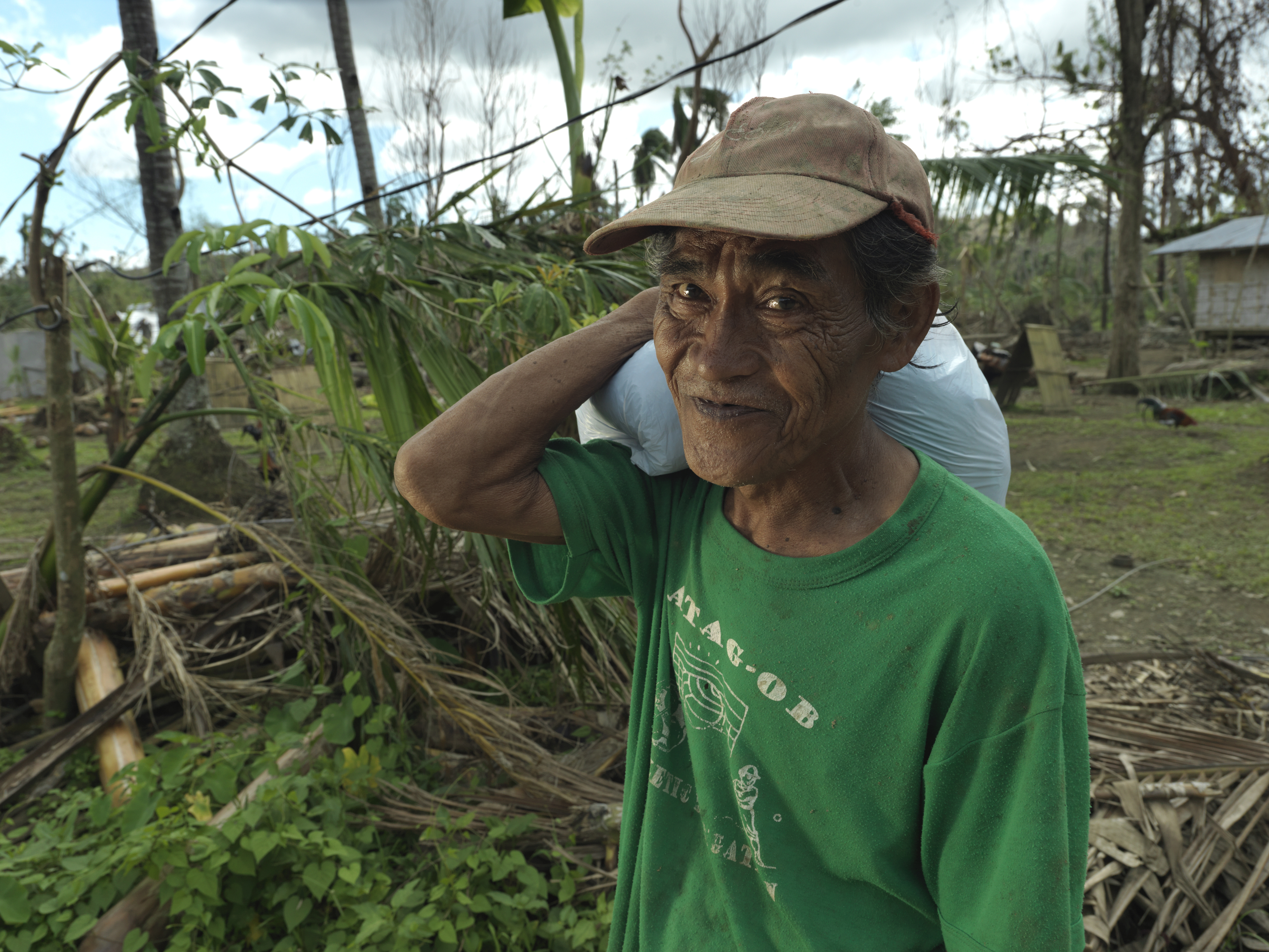 Older man carries a food pack after Typhoon Haiyan.