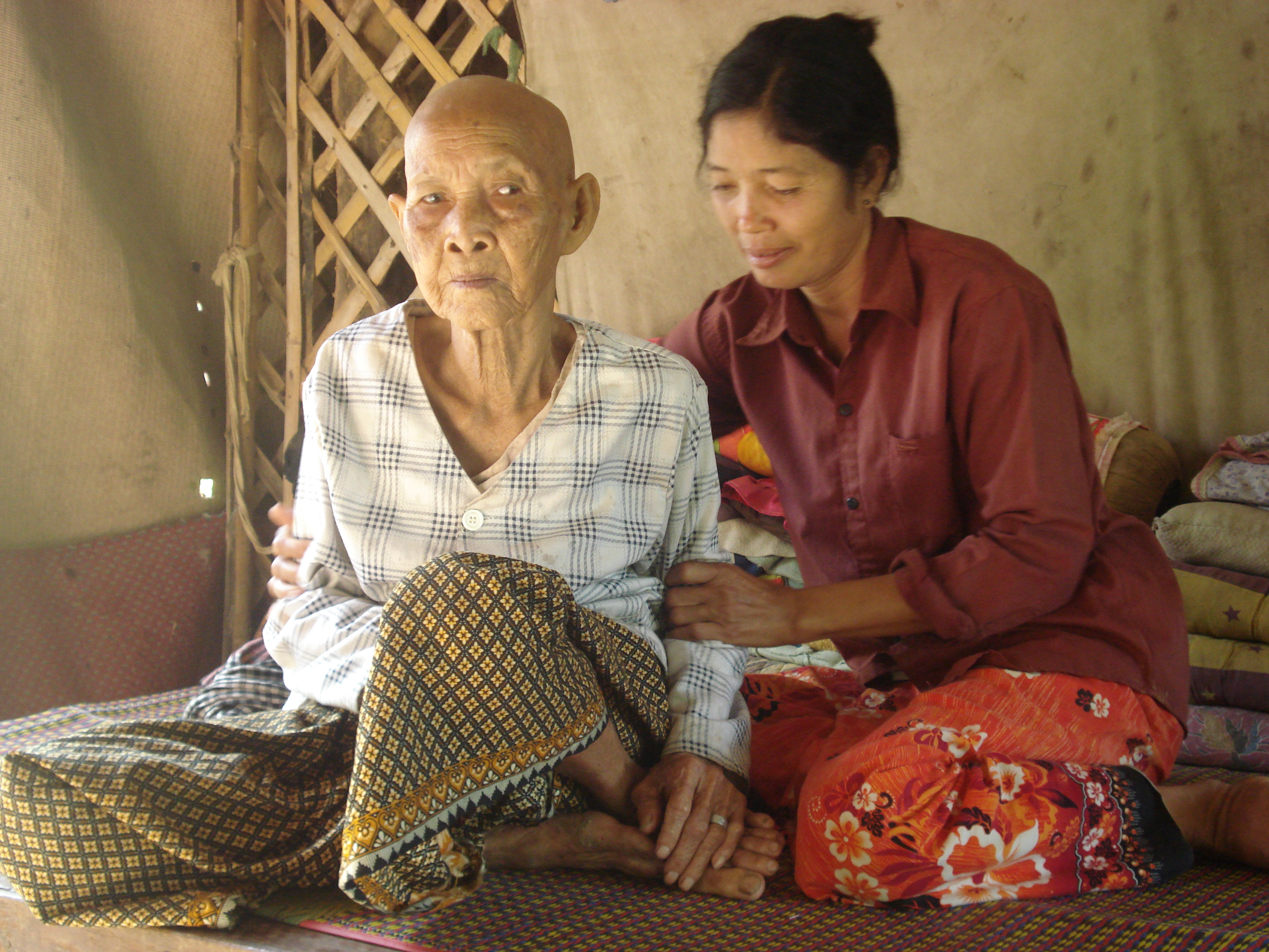 An older woman in Myanmar is visited by a health volunteer.