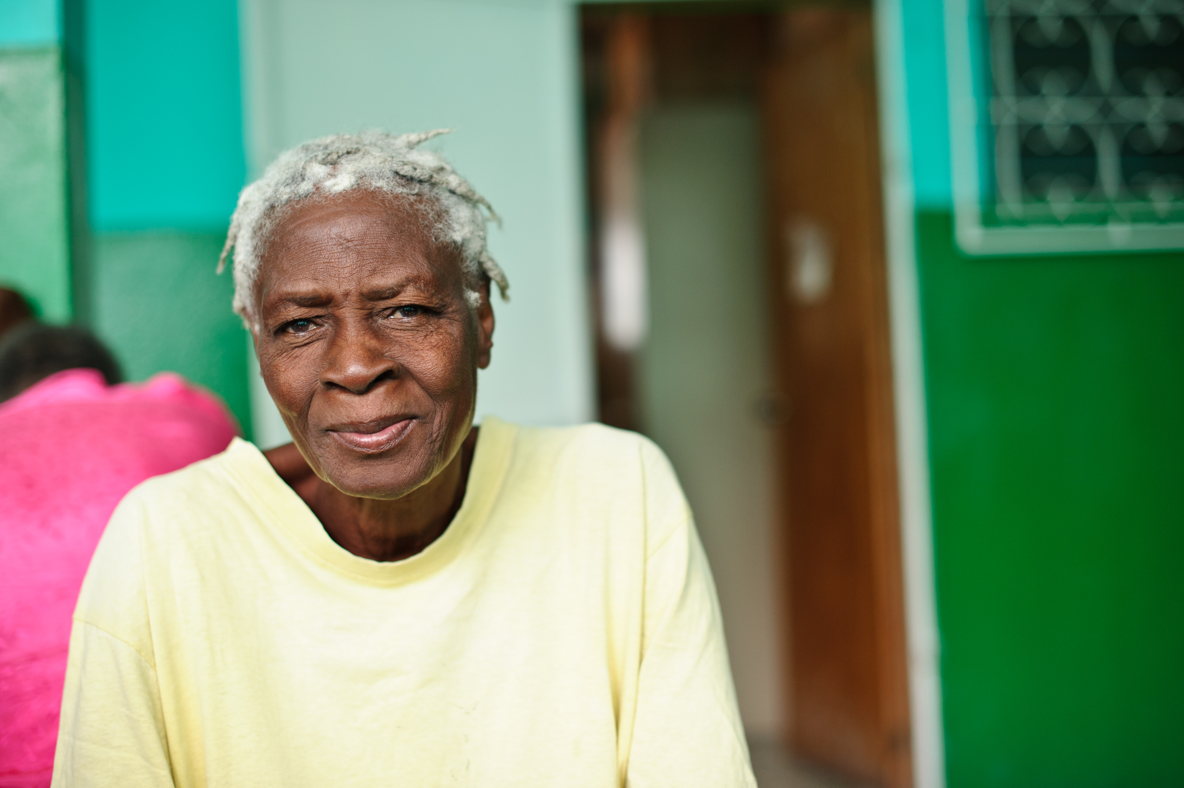 An older woman from Haiti calmly smiles.