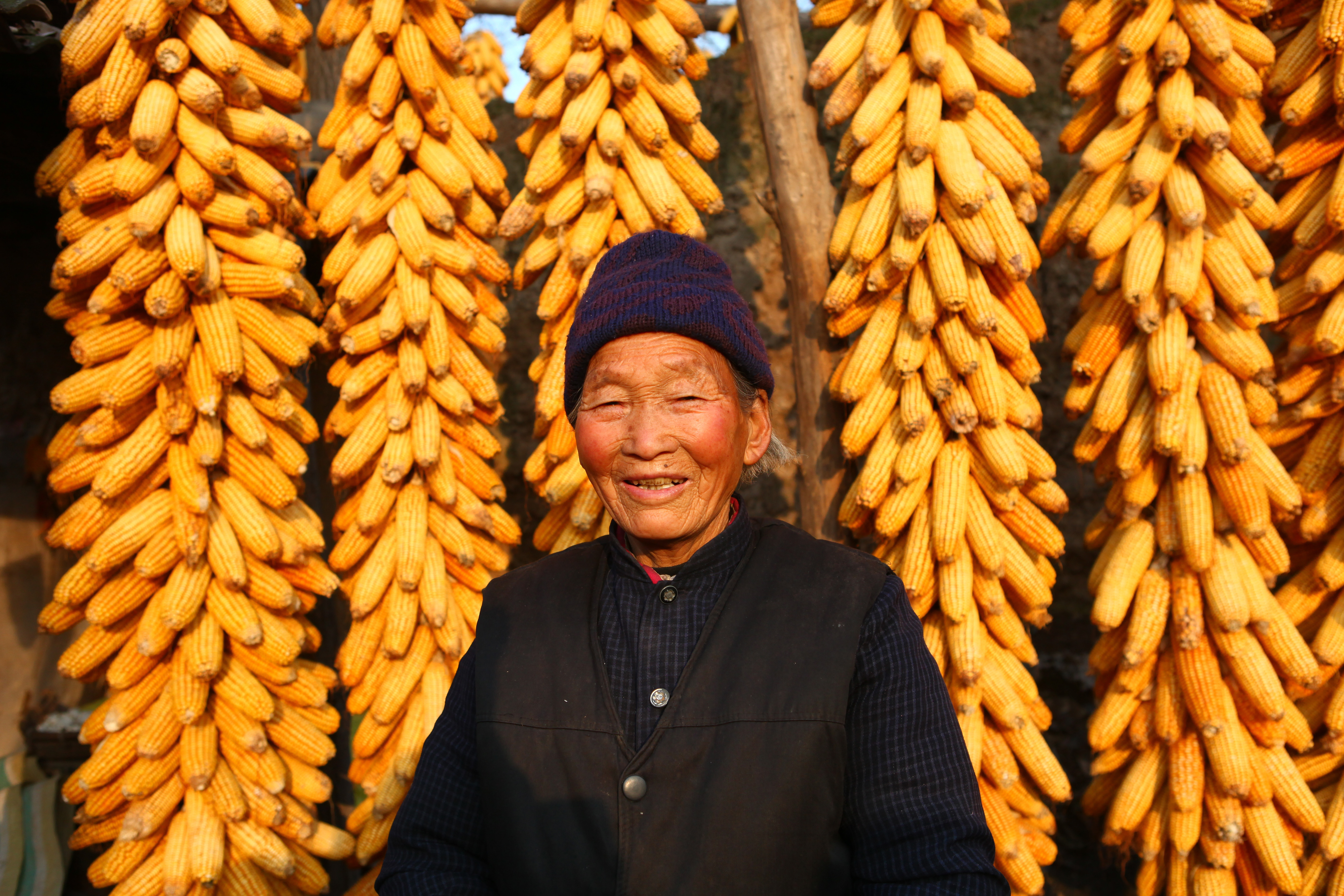 An older woman smiles in front of her corn shop.