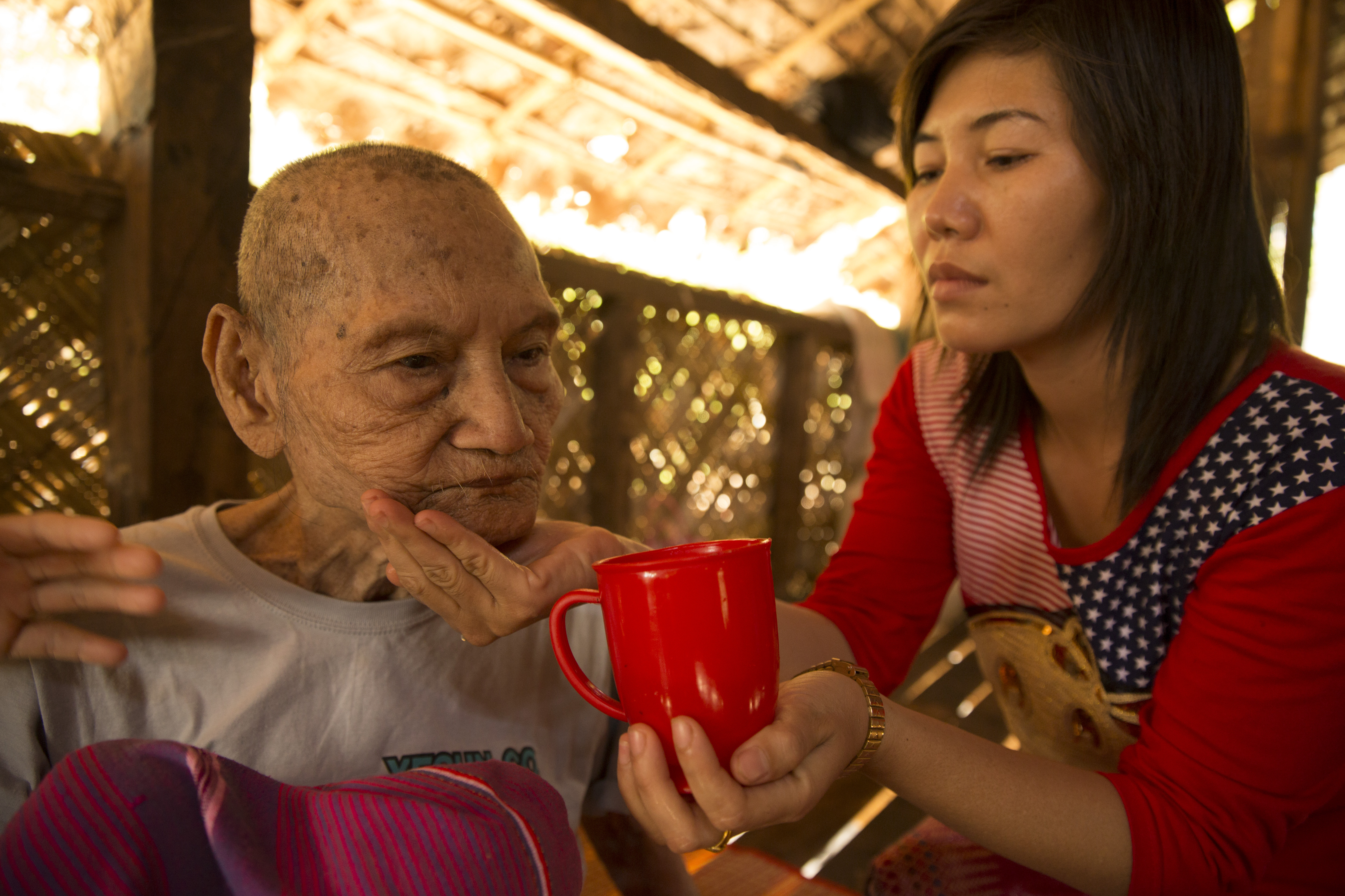 A homecare volunteer helps U Ne Nyunt to eat in Myanmar.