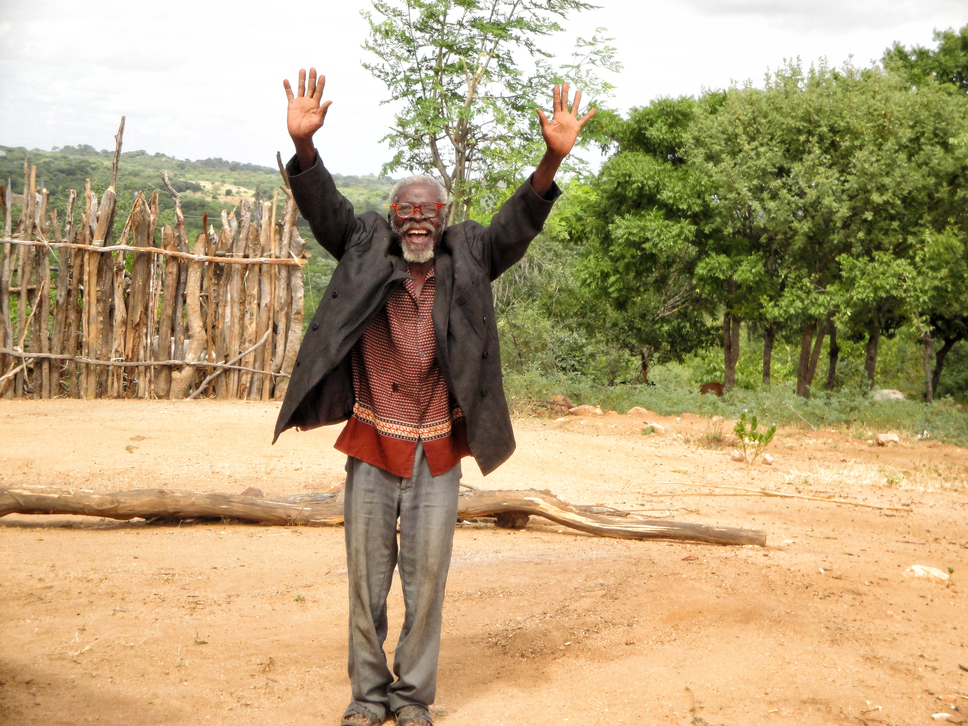 An older man raises his hands with happiness in Mozambique.