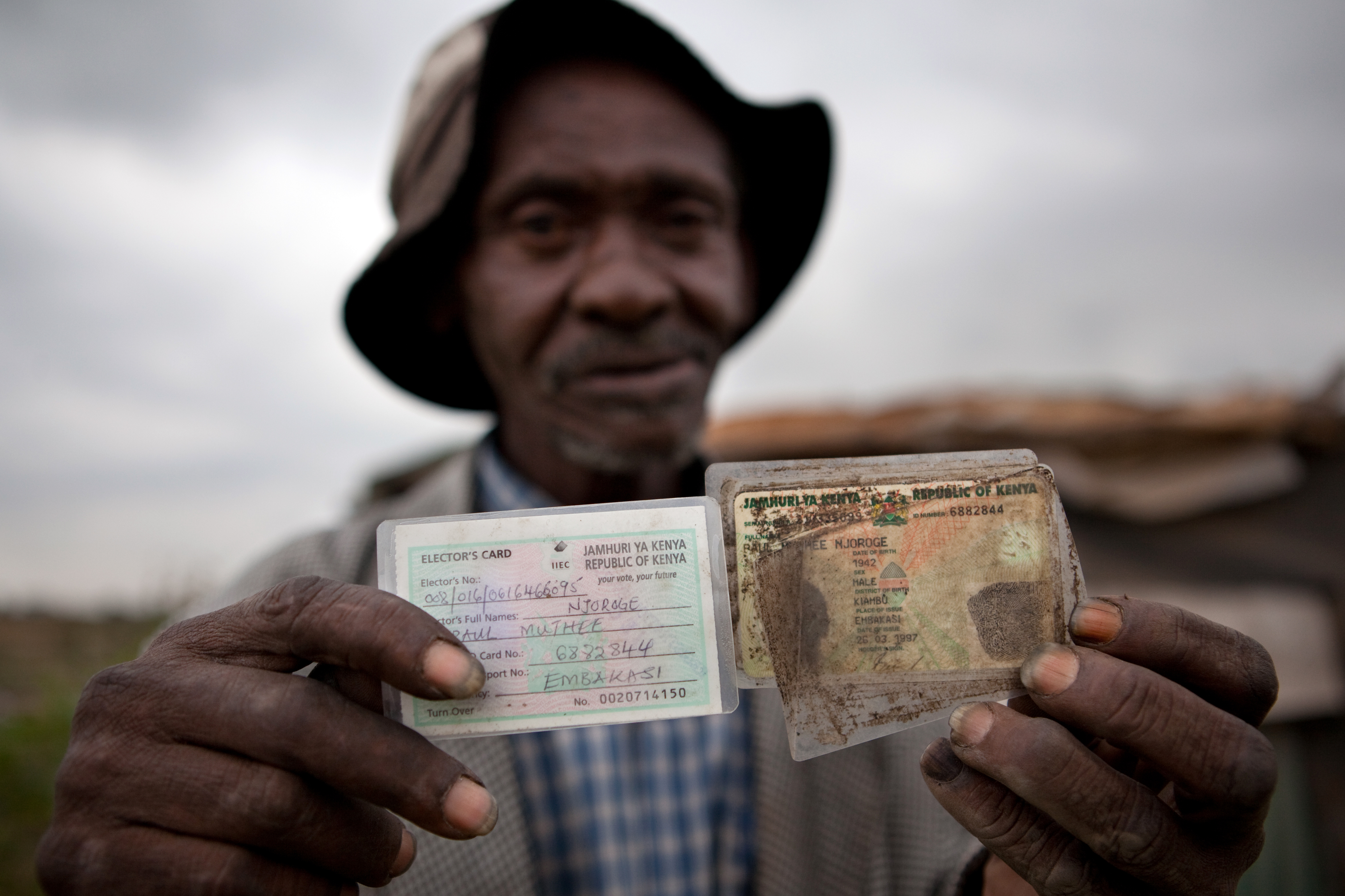 Paul, Mozambique, holds up the ID card which allows him to access his pension.